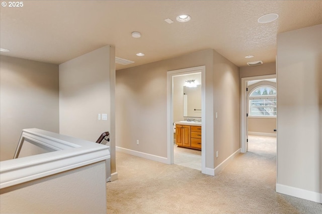 corridor featuring recessed lighting, visible vents, baseboards, and light colored carpet