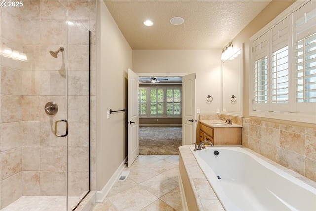 bathroom with vanity, a garden tub, a stall shower, a textured ceiling, and a ceiling fan