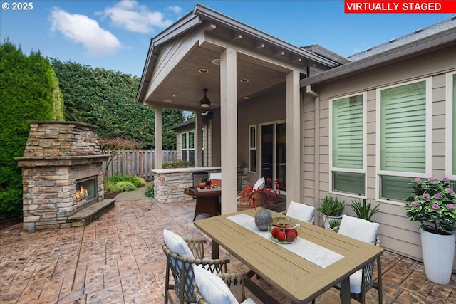 view of patio featuring outdoor dining area, fence, and an outdoor stone fireplace