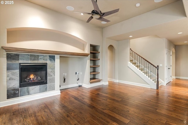 unfurnished living room featuring hardwood / wood-style floors, stairway, built in features, baseboards, and ceiling fan