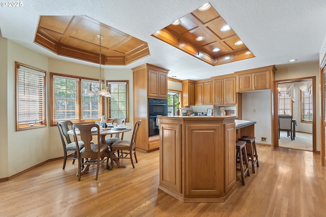 5844 Ridgetop Ct, Lake Oswego, OR 97035 - kitchen featuring coffered ceiling, light wood-style floors, plenty of natural light, a kitchen island, and light countertops