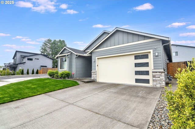 5009 NE 85th St, Vancouver, WA 98665 - view of front of house with a garage, stone siding, board and batten siding, concrete driveway, and fence