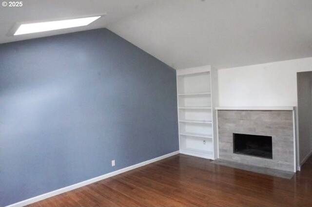 4768 Manzanita St, Eugene, OR 97405 - unfurnished living room featuring built in shelves, wood finished floors, vaulted ceiling, a tiled fireplace, and baseboards