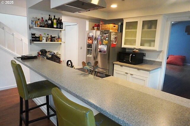 4768 Manzanita St, Eugene, OR 97405 - kitchen with stainless steel refrigerator with ice dispenser, black microwave, a breakfast bar, glass insert cabinets, and range hood