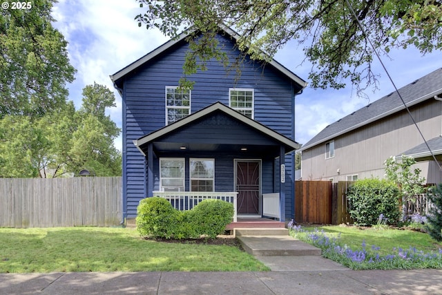 traditional-style home with a front lawn, fence, and covered porch