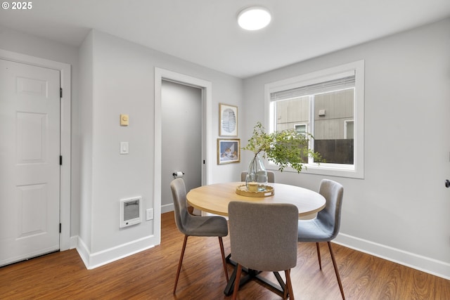 dining space with baseboards, heating unit, and wood finished floors