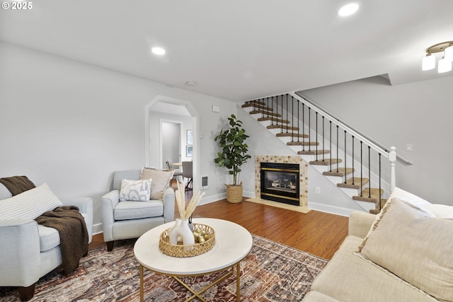 living room featuring wood finished floors, baseboards, stairway, recessed lighting, and arched walkways