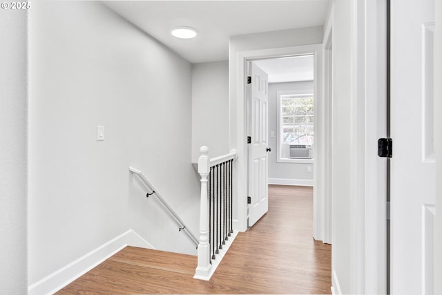 corridor with baseboards, cooling unit, wood finished floors, and an upstairs landing