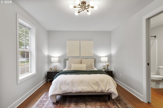 bedroom with dark wood-style flooring, baseboards, and a notable chandelier