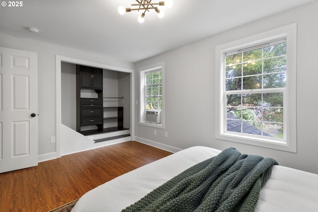 bedroom featuring baseboards, a closet, wood finished floors, and a chandelier