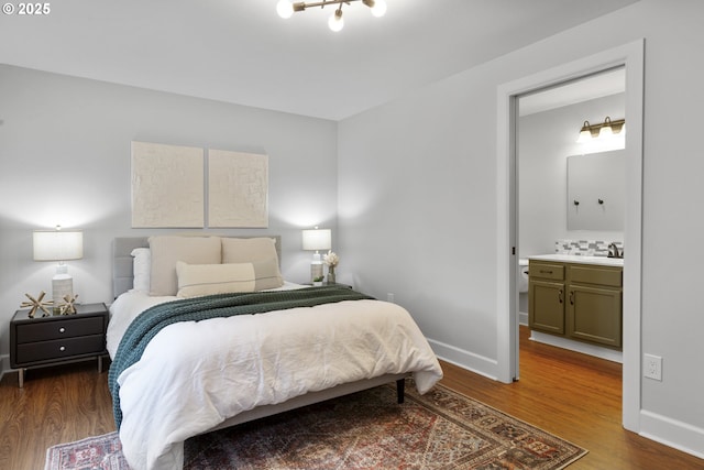 bedroom featuring baseboards, a sink, ensuite bathroom, and wood finished floors