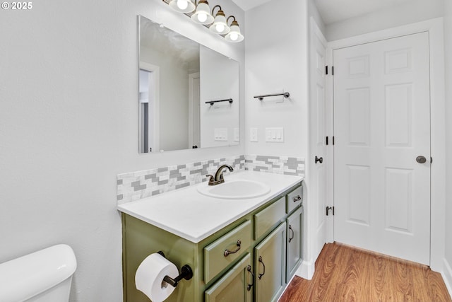 bathroom with vanity, decorative backsplash, toilet, and wood finished floors