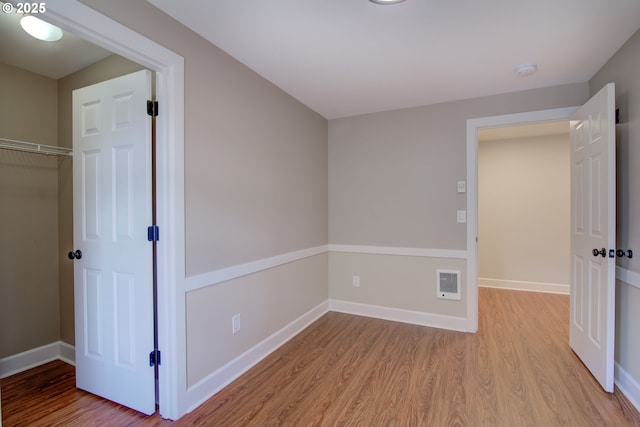 unfurnished bedroom featuring baseboards, wood finished floors, and a closet