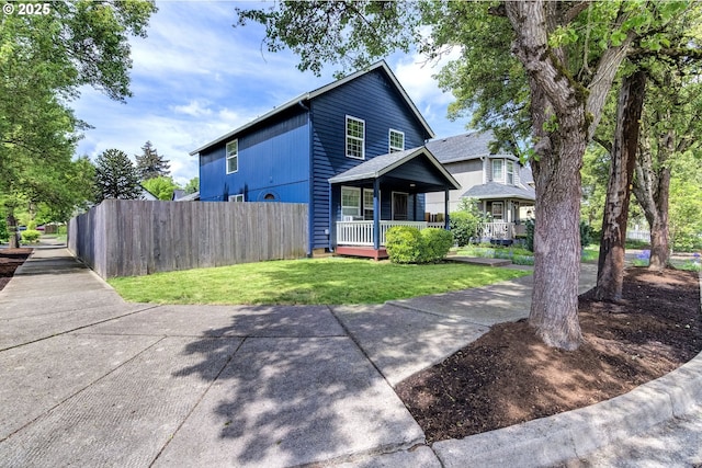 view of front of property featuring fence, a porch, and a front lawn
