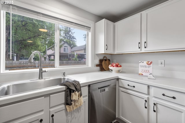 kitchen featuring stainless steel dishwasher, white cabinetry, a sink, and light countertops