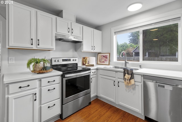 kitchen with appliances with stainless steel finishes, a sink, light countertops, under cabinet range hood, and white cabinetry