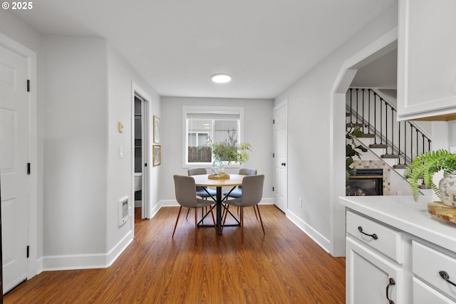dining area featuring baseboards, stairs, wood finished floors, and arched walkways