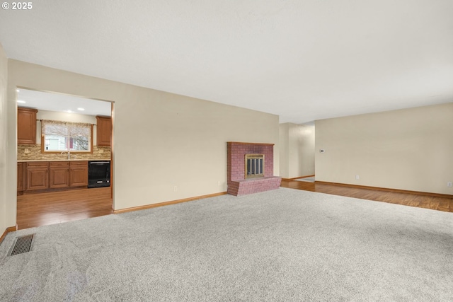 unfurnished living room featuring sink, light carpet, and a fireplace