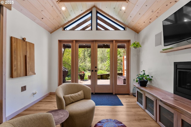 living area with french doors, a glass covered fireplace, high vaulted ceiling, light wood-style flooring, and recessed lighting