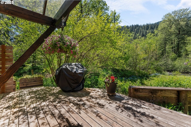 deck with a wooded view and area for grilling