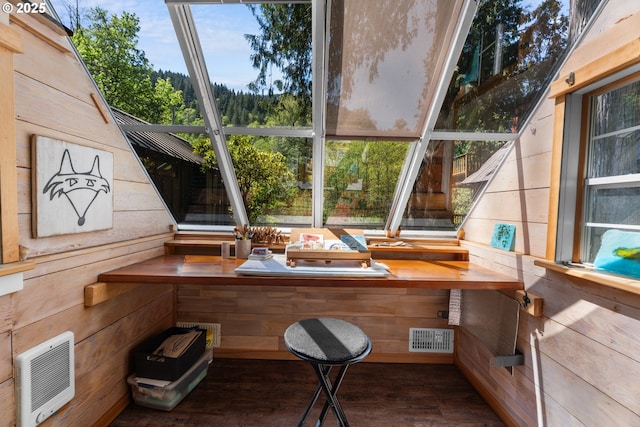 home office with wood walls, heating unit, and wood finished floors