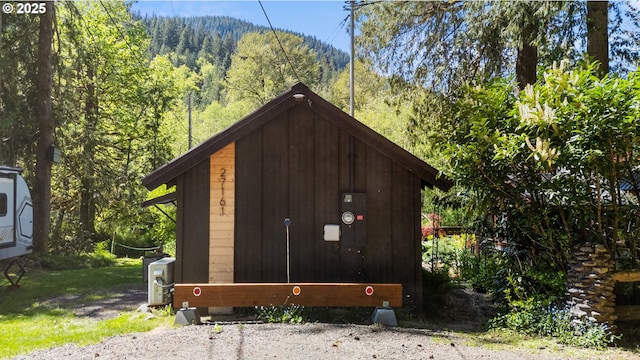 view of outdoor structure featuring a wooded view and a mountain view