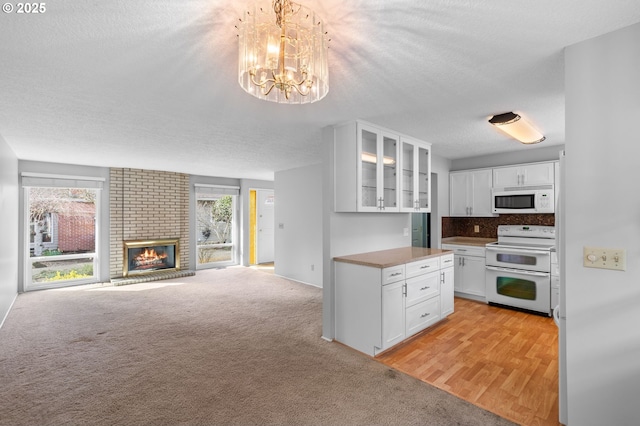 5016 SW Normandy Pl, Beaverton, OR 97005 - kitchen featuring white appliances, white cabinets, a chandelier, glass insert cabinets, and open floor plan