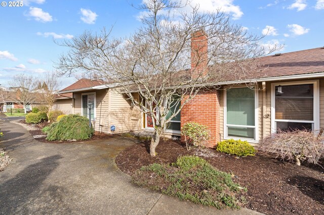 5016 SW Normandy Pl, Beaverton, OR 97005 - view of property exterior with a chimney, brick siding, and roof with shingles