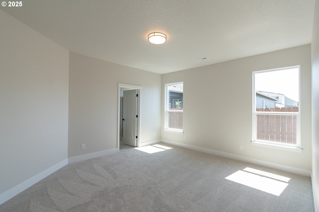 unfurnished room with visible vents, baseboards, and light carpet