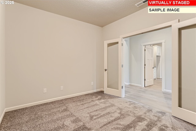 unfurnished room with carpet, visible vents, a textured ceiling, and baseboards