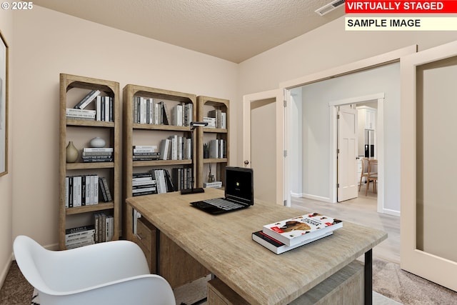 office space with a textured ceiling, light wood finished floors, baseboards, and visible vents