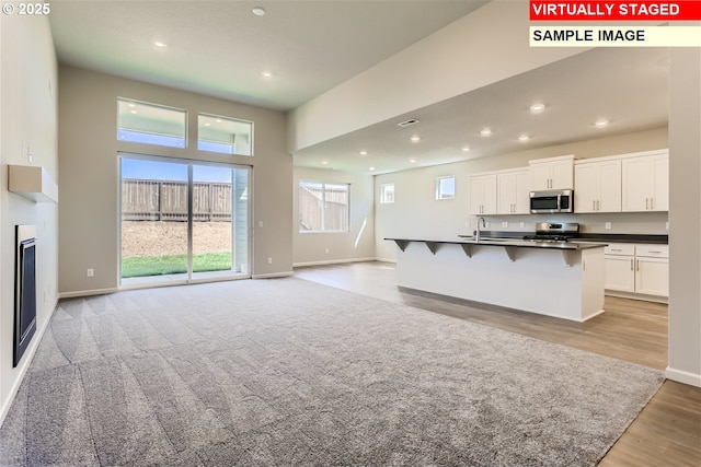 kitchen featuring white cabinets, dark countertops, open floor plan, and appliances with stainless steel finishes