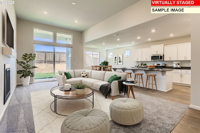 living room featuring light wood-type flooring, baseboards, and recessed lighting