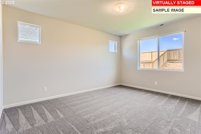 carpeted empty room featuring visible vents, baseboards, and a textured ceiling