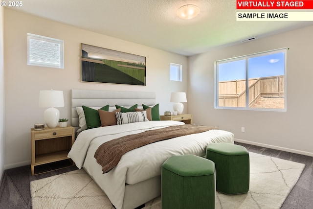 carpeted bedroom with a textured ceiling, baseboards, and visible vents