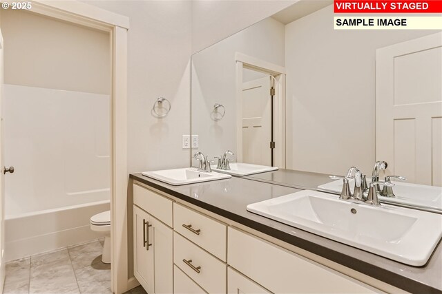 bathroom with toilet, double vanity, and a sink