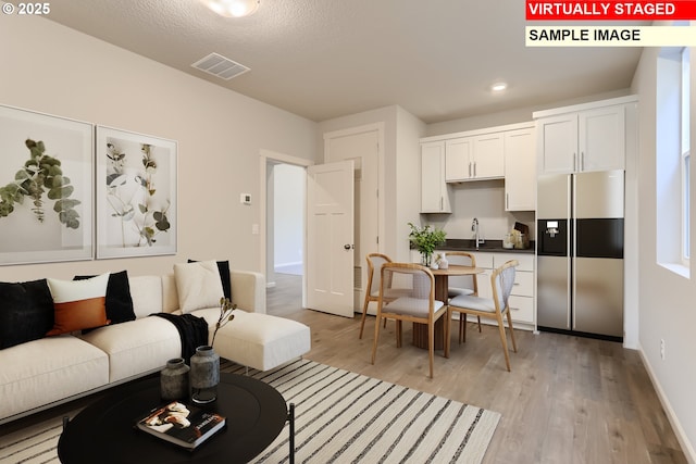 living room featuring visible vents, baseboards, light wood finished floors, and recessed lighting