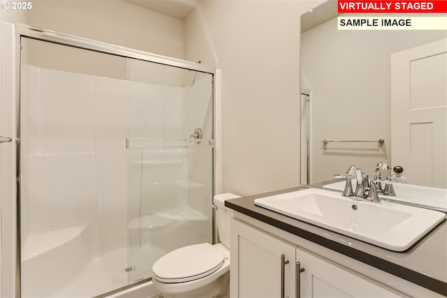 bathroom with toilet, a shower stall, and vanity