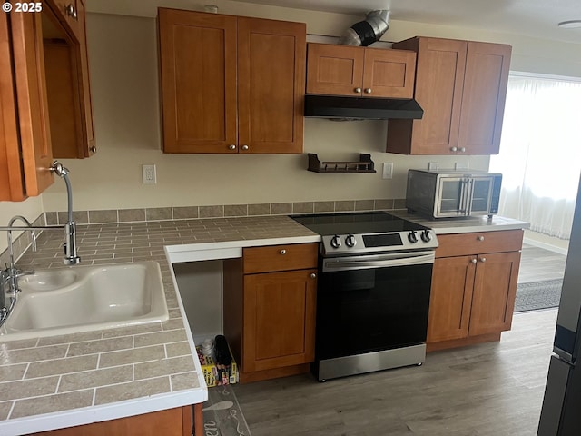 865 E Columbia River Hwy, Clatskanie, OR 97016 - kitchen with stainless steel electric range oven, under cabinet range hood, a sink, and brown cabinets