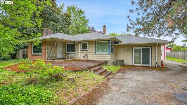 bungalow-style home with a chimney, fence, roof with shingles, and a patio