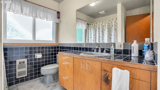 full bathroom with heating unit, toilet, tile walls, wainscoting, and vanity