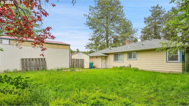 rear view of property featuring a chimney and an outdoor structure