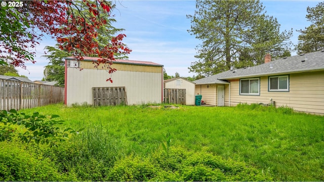 view of yard with fence and an outbuilding