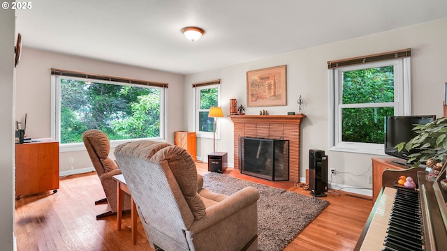 living area featuring wood finished floors, baseboards, and a brick fireplace