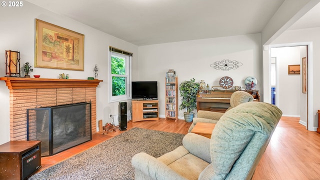 living area with a fireplace, baseboards, and wood finished floors