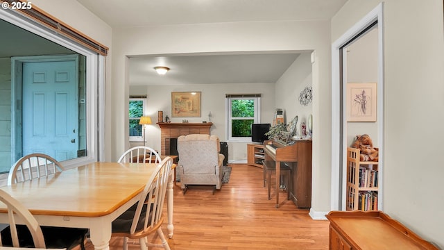 dining room with light wood-style floors and a brick fireplace