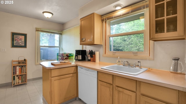 kitchen with white dishwasher, a sink, light countertops, a peninsula, and baseboards