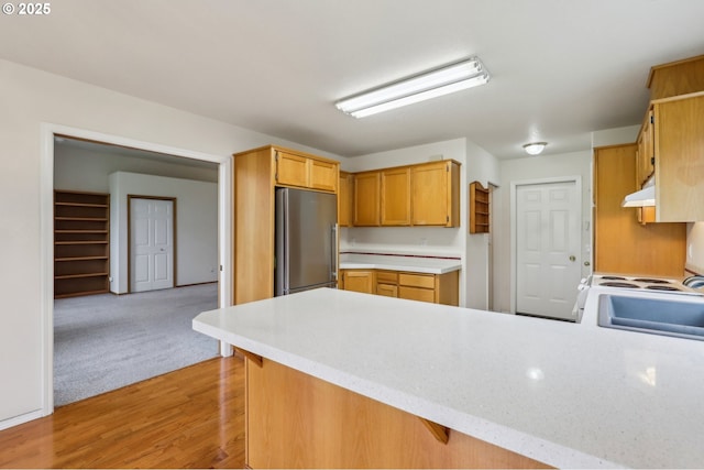 33333 Adam Ct, Scappoose, OR 97056 - kitchen with stainless steel refrigerator, under cabinet range hood, a peninsula, light countertops, and light wood-style floors