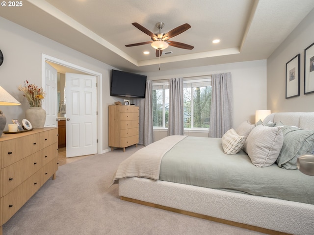 bedroom with a tray ceiling, recessed lighting, visible vents, and light carpet