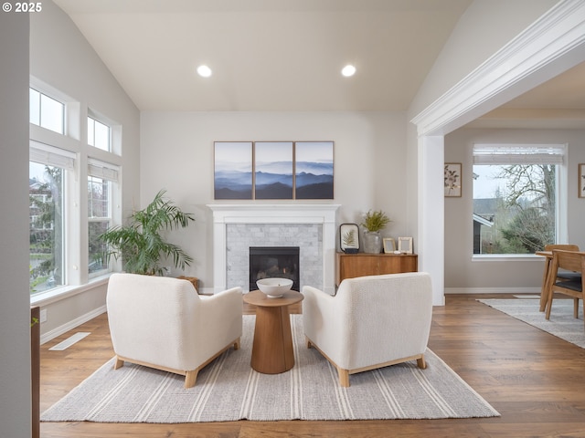 living area featuring vaulted ceiling, baseboards, and wood finished floors